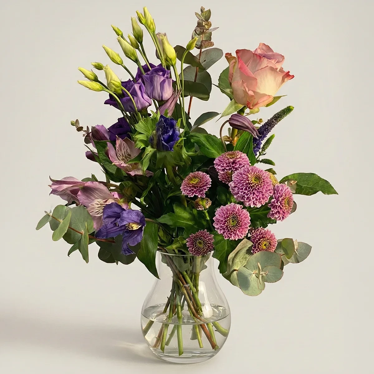 Lila blombukett av färska snittblommor i glasvas från Nockebyhovs Blommor i Bromma, Stockholm.