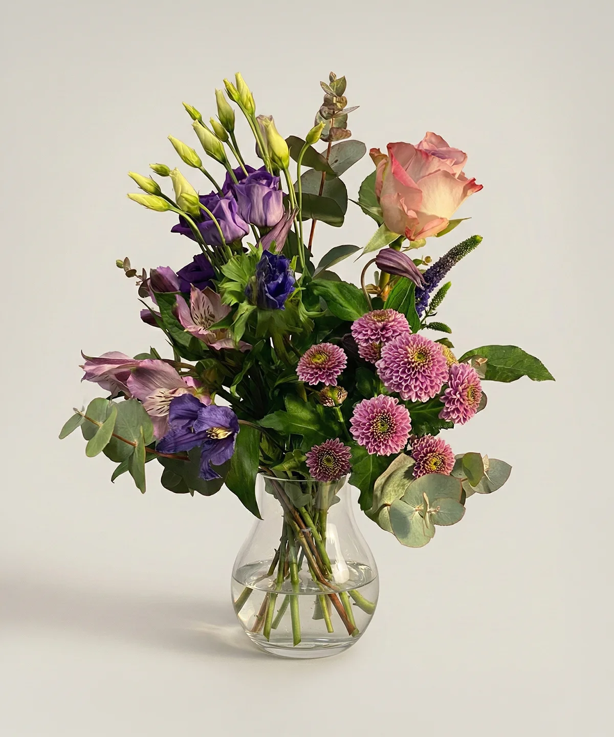Lila blombukett av färska snittblommor i glasvas från Nockebyhovs Blommor i Bromma, Stockholm.