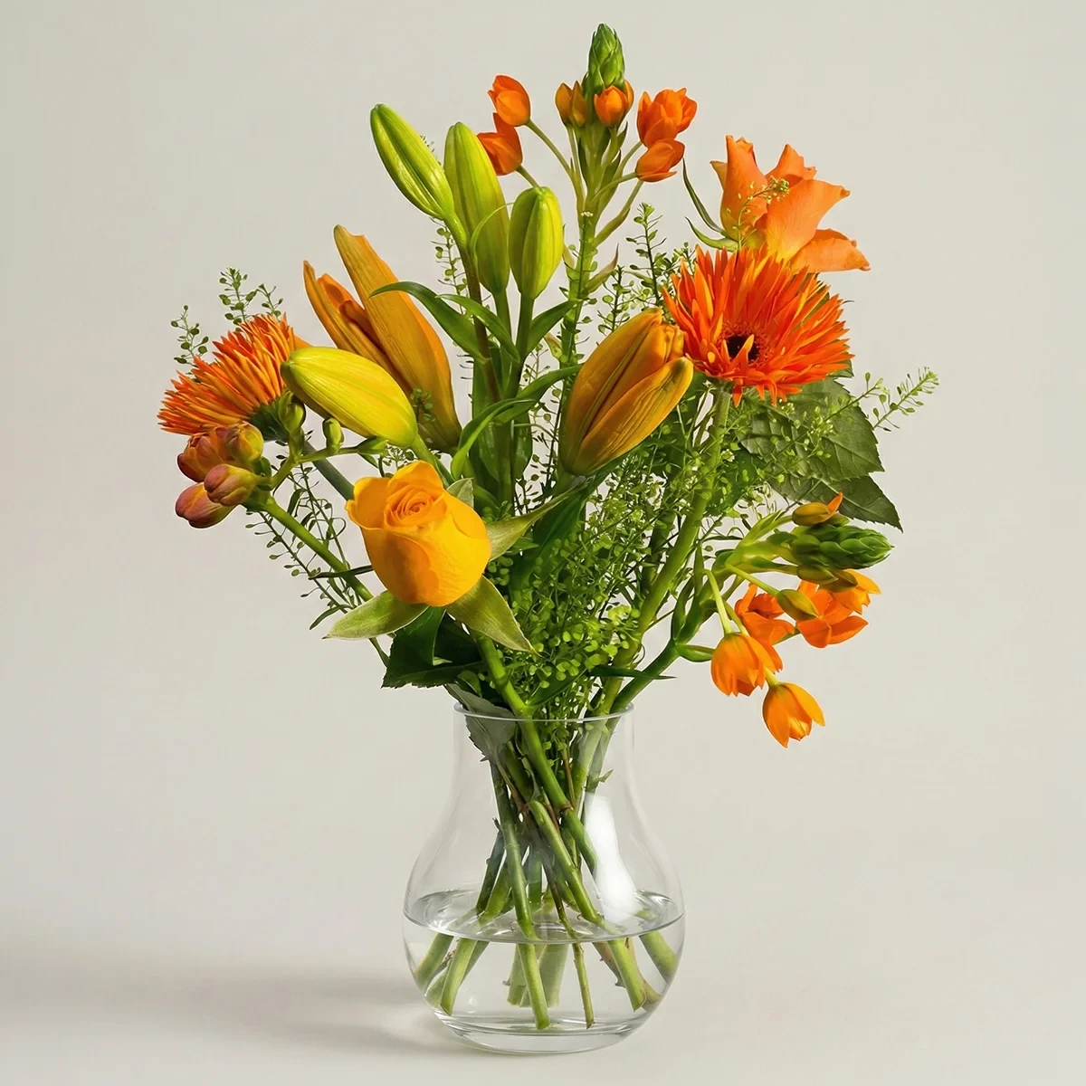Orange blombukett av färska snittblommor i glasvas från Nockebyhovs Blommor i Bromma, Stockholm.