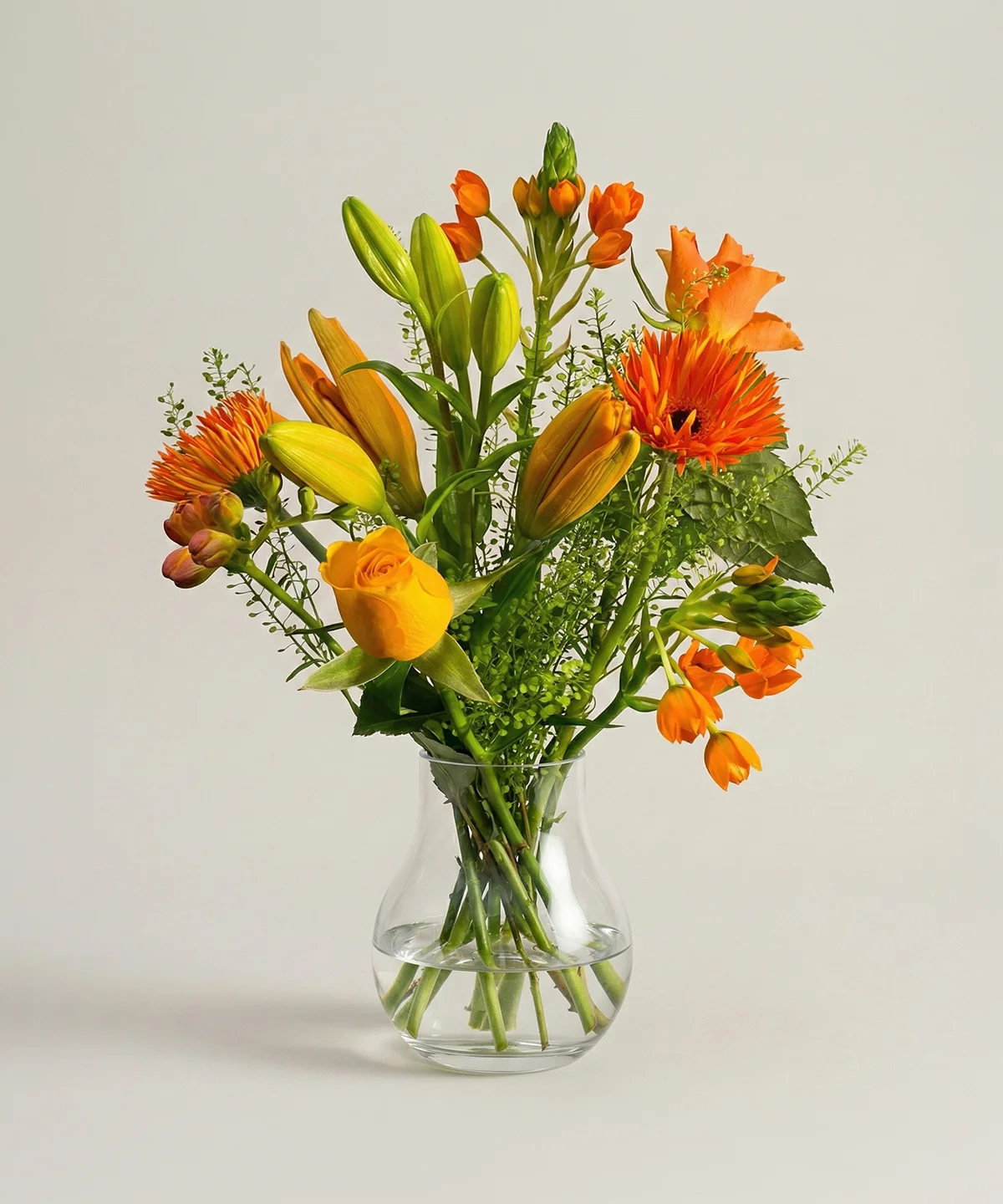 Orange blombukett av färska snittblommor i glasvas från Nockebyhovs Blommor i Bromma, Stockholm.